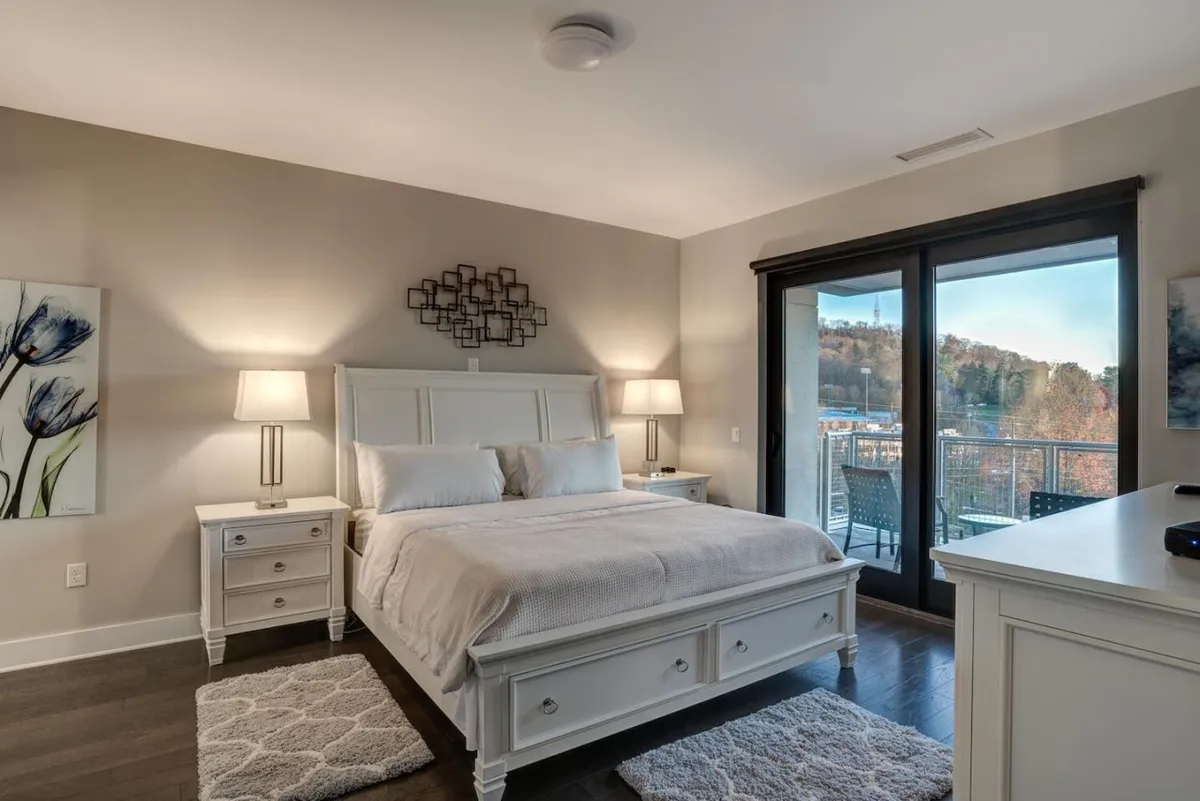 A second elegant bedroom featuring a well-made bed, tasteful wall art, and glass doors that lead onto a private balcony. The serene atmosphere is enhanced by sunlight filtering into the room, and the balcony provides another opportunity to enjoy the mountain scenery and fresh air.