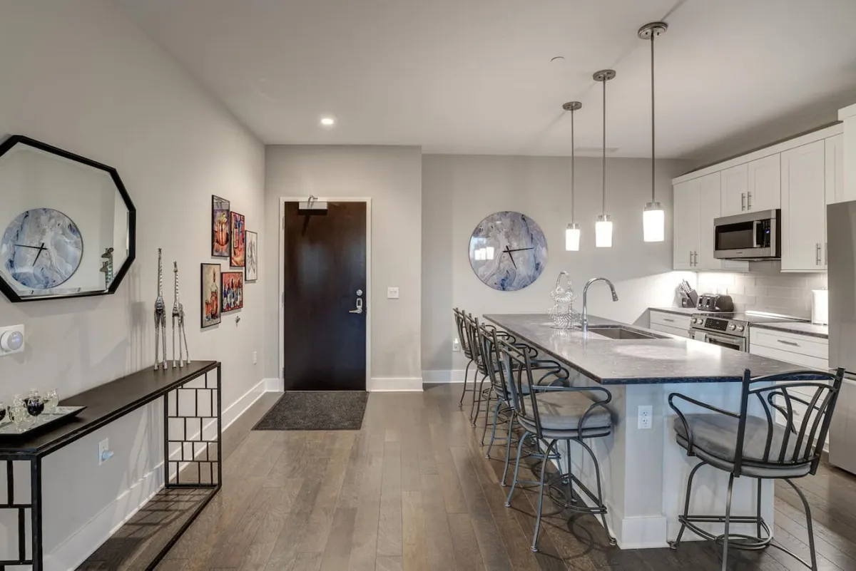 A sleek, modern kitchen with a central island, bar stools, and decorative wall art. The space is designed for both cooking and entertaining, with an inviting ambiance that encourages interaction and culinary creativity.