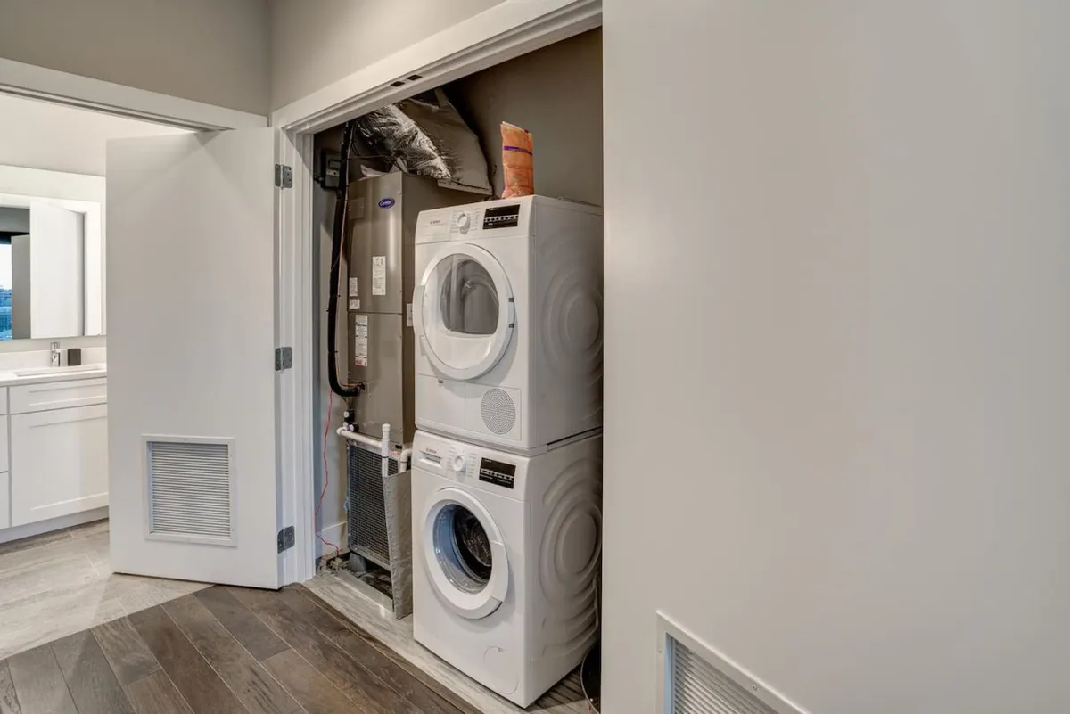 A bright laundry space equipped with a washing machine and dryer, with a large mirror in the background. The scene is clean, organized, and practical, highlighting convenience and efficiency.
